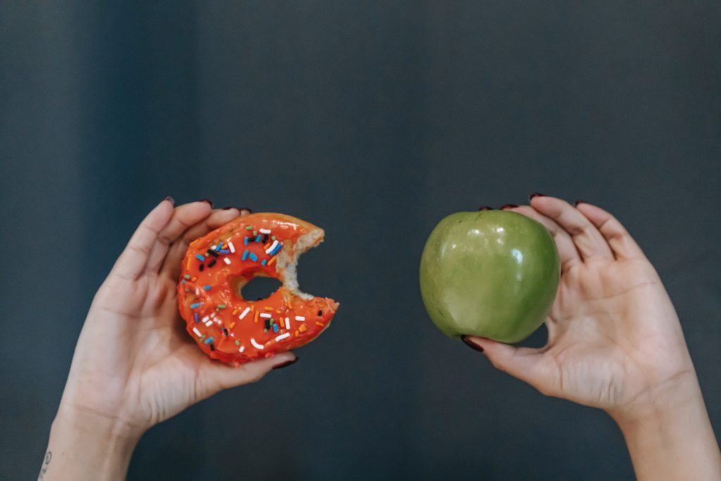 Hands holding a donut and a apple