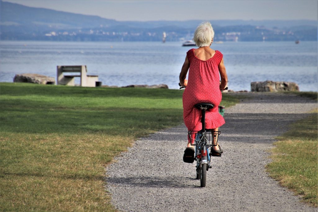 A woman over 50 riding best e-bike for arthritic knees near a lake.