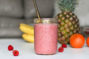 Smoothie in a jar on a table next to some fruit