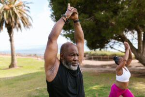 A man and woman doing yoga outside.